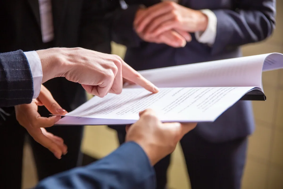 Three people reviewing a printed document together at a table