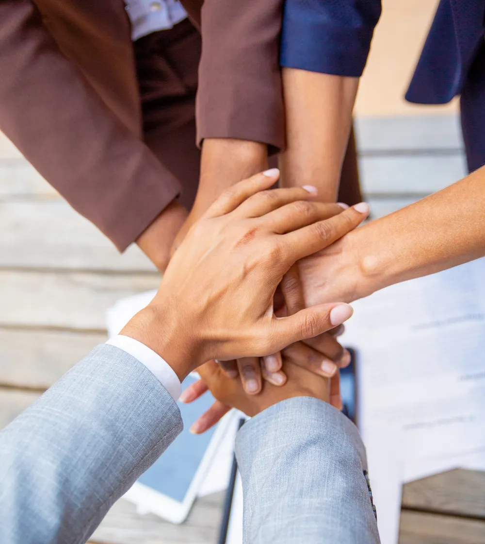 A group of colleagues joining hands over a table